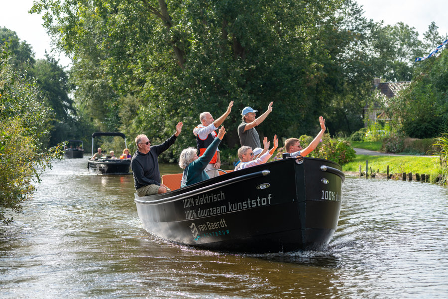 Een groep zwaaiende mensen die zwaaien op een elektrische sloep